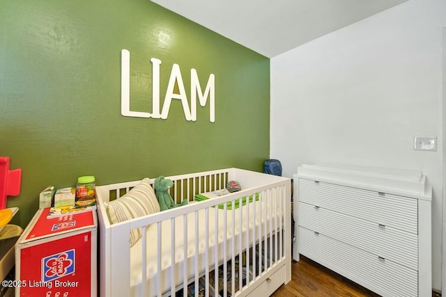 bedroom featuring a crib and wood finished floors