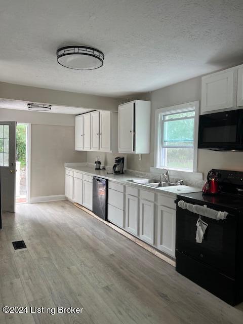 kitchen with sink, black appliances, white cabinets, and light wood-type flooring