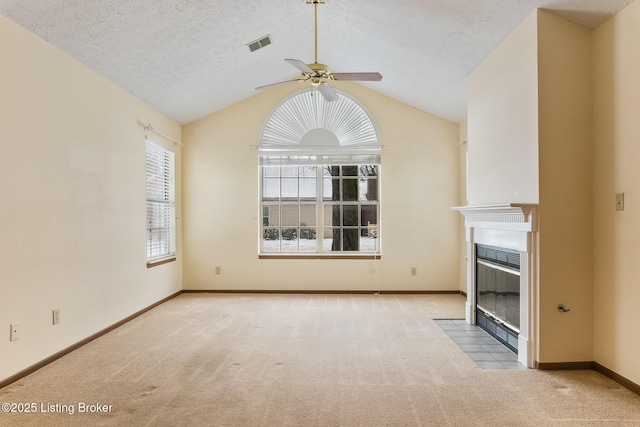 unfurnished living room with vaulted ceiling, light colored carpet, ceiling fan, and a textured ceiling