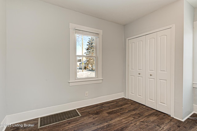 unfurnished bedroom featuring dark hardwood / wood-style flooring and a closet