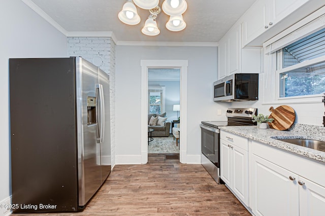 kitchen featuring crown molding, appliances with stainless steel finishes, white cabinets, and light hardwood / wood-style floors