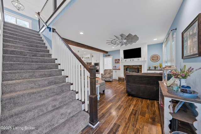 staircase with a notable chandelier, a fireplace, wood finished floors, and recessed lighting