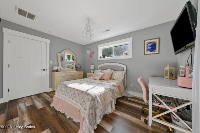 bedroom featuring an inviting chandelier, visible vents, and wood finished floors