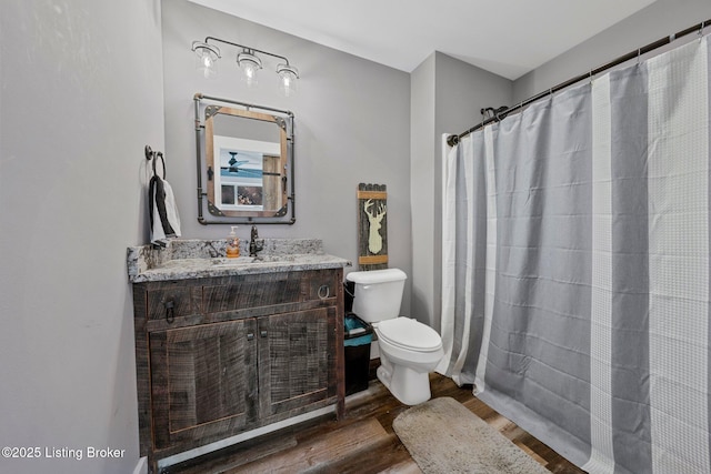 full bathroom with toilet, a shower with shower curtain, wood finished floors, and vanity