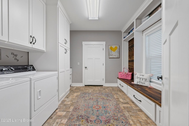 laundry area featuring stone finish flooring, cabinet space, baseboards, and separate washer and dryer