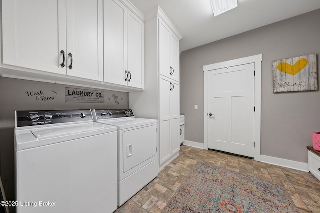 clothes washing area with stone finish flooring, washing machine and dryer, cabinet space, and baseboards