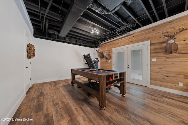 recreation room featuring french doors, wood walls, baseboards, and wood finished floors