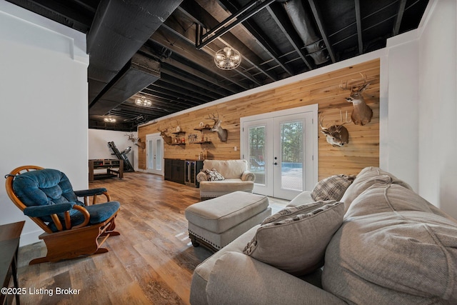 living room with french doors, wood walls, and wood finished floors