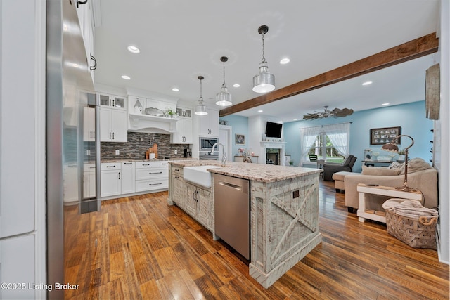 kitchen featuring white cabinets, dishwasher, open floor plan, dark wood-type flooring, and a sink