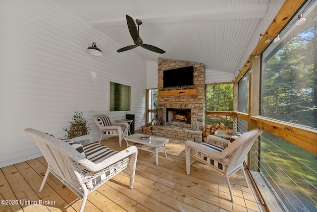 sunroom / solarium with lofted ceiling with beams, an outdoor stone fireplace, and a ceiling fan