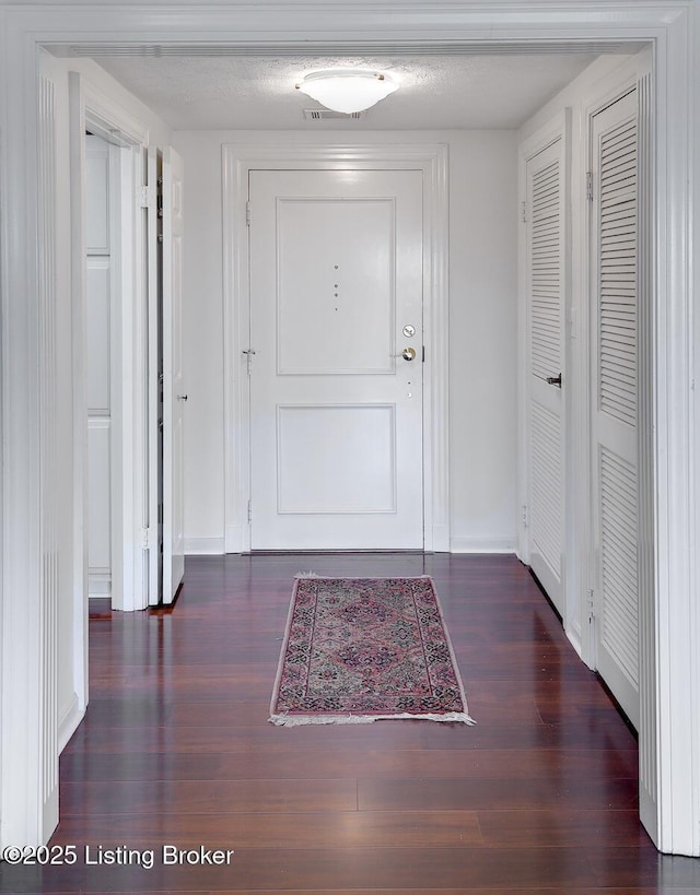 doorway featuring dark wood-type flooring and a textured ceiling