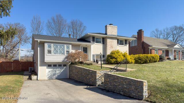 view of front of house featuring a garage, a front lawn, and central air condition unit