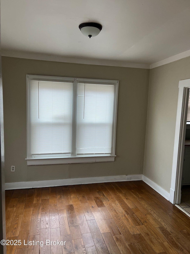 empty room with crown molding, dark hardwood / wood-style floors, and a wealth of natural light