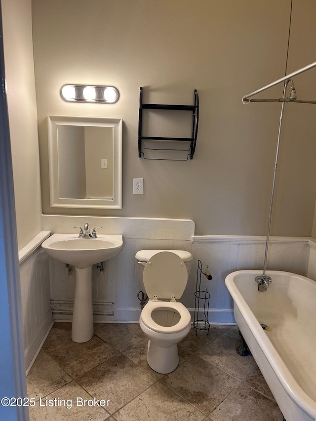 bathroom with toilet, a bathing tub, and sink