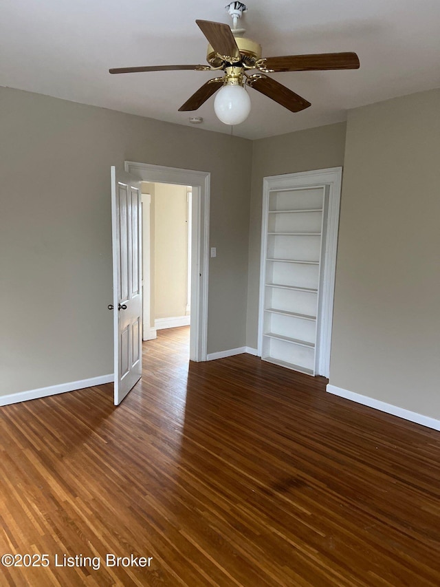 empty room featuring dark hardwood / wood-style floors, ceiling fan, and built in shelves