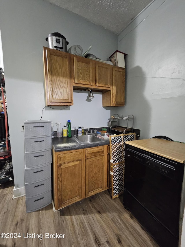 kitchen with dark hardwood / wood-style flooring, sink, a textured ceiling, and black dishwasher