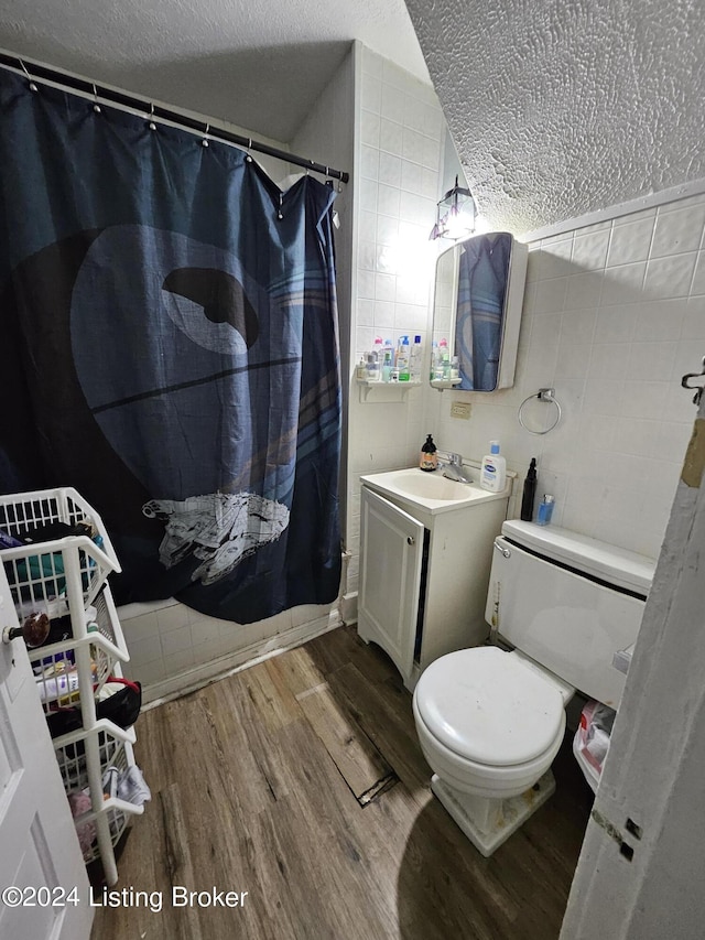 bathroom with hardwood / wood-style flooring, tile walls, vanity, a textured ceiling, and curtained shower