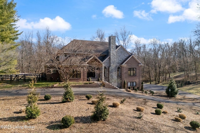 view of front of house with a chimney, fence, and brick siding