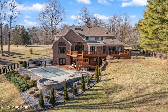 rear view of house featuring a lawn, a patio, fence, a deck, and brick siding