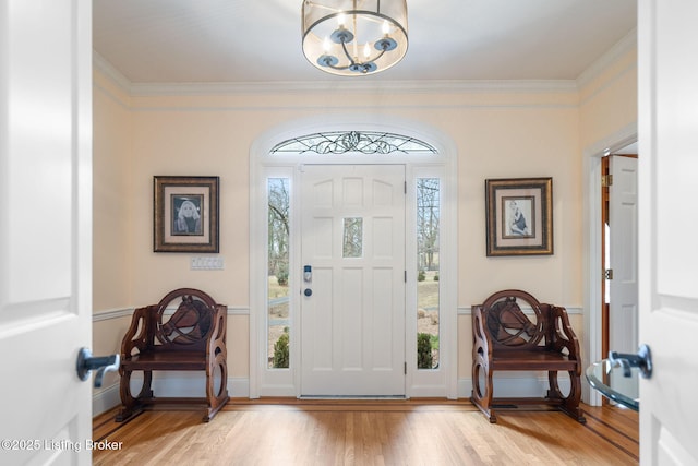 foyer featuring ornamental molding, a notable chandelier, plenty of natural light, and light wood-style flooring