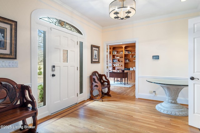 foyer featuring light wood-style floors, a chandelier, and crown molding