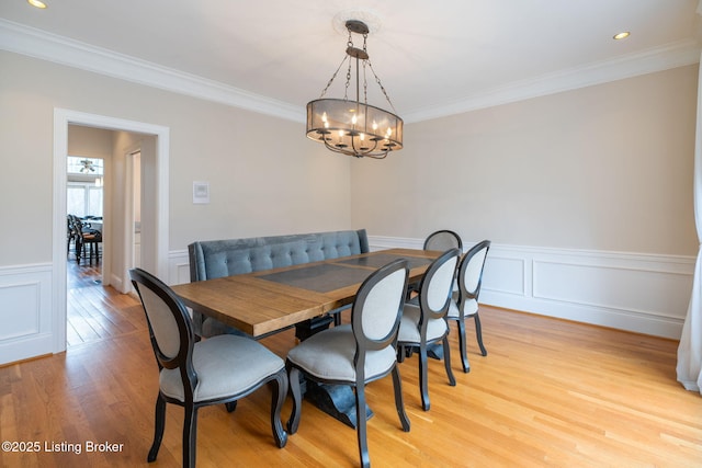 dining area featuring a wainscoted wall, ornamental molding, and light wood-style floors