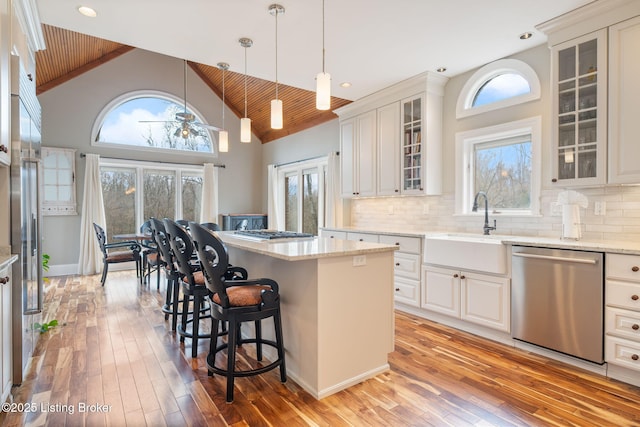 kitchen with stainless steel appliances, a center island, white cabinetry, and glass insert cabinets