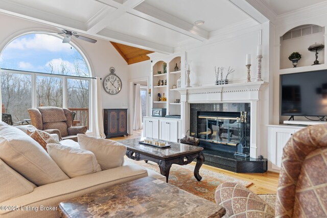 living room with light wood-style flooring, built in shelves, ornamental molding, and a fireplace