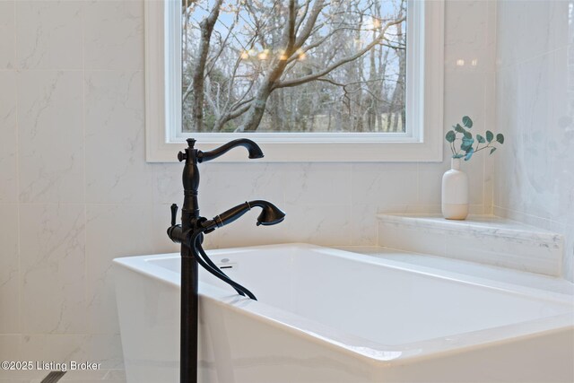 bathroom featuring a sink, tile walls, and a bath