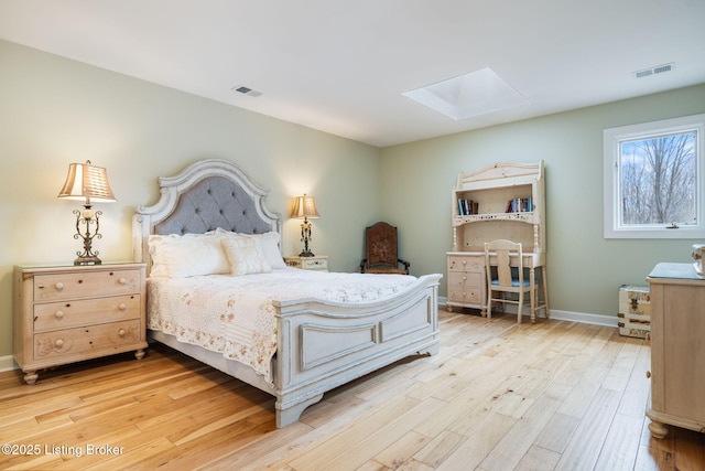 bedroom with a skylight, light wood-style flooring, visible vents, and baseboards