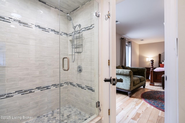 ensuite bathroom featuring ensuite bathroom, wood finished floors, visible vents, and a shower stall