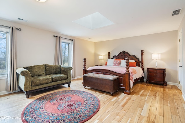 bedroom featuring light wood-type flooring, a skylight, and visible vents