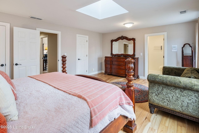 bedroom with a skylight, baseboards, visible vents, and light wood-style floors