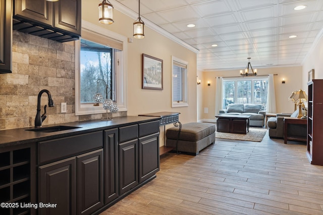 kitchen featuring a sink, open floor plan, tasteful backsplash, dark countertops, and decorative light fixtures