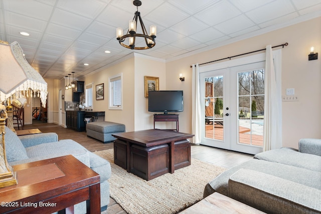 living room with french doors, recessed lighting, light wood-style floors, and an inviting chandelier