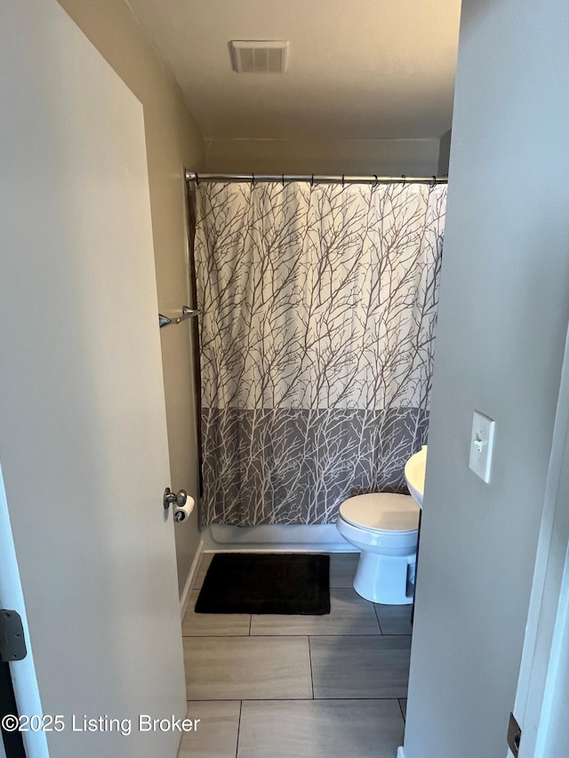 bathroom featuring toilet, a shower with shower curtain, and visible vents