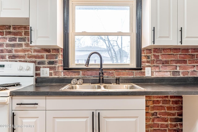 kitchen with white cabinetry, brick wall, sink, and white range oven