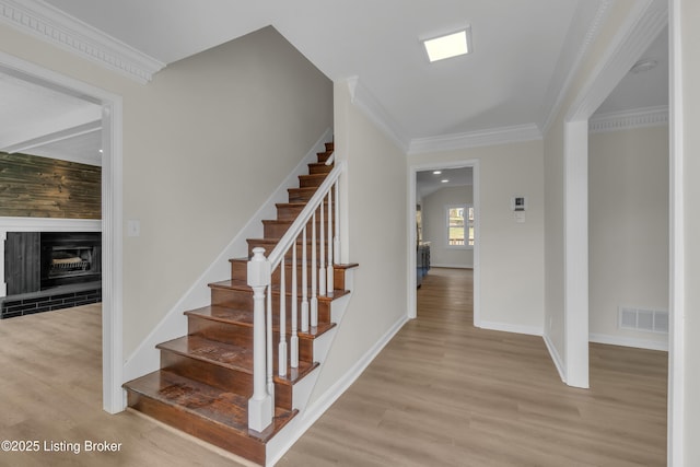 stairs featuring ornamental molding, a fireplace, and hardwood / wood-style floors