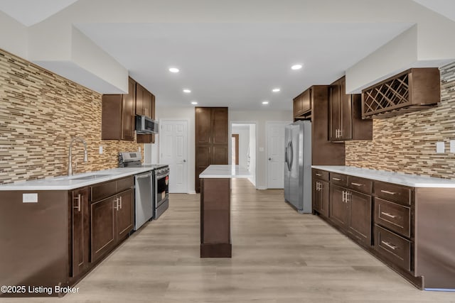 kitchen with tasteful backsplash, sink, dark brown cabinetry, light hardwood / wood-style floors, and stainless steel appliances