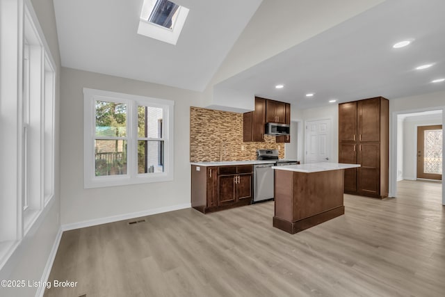 kitchen with decorative backsplash, a wealth of natural light, stainless steel appliances, and a center island