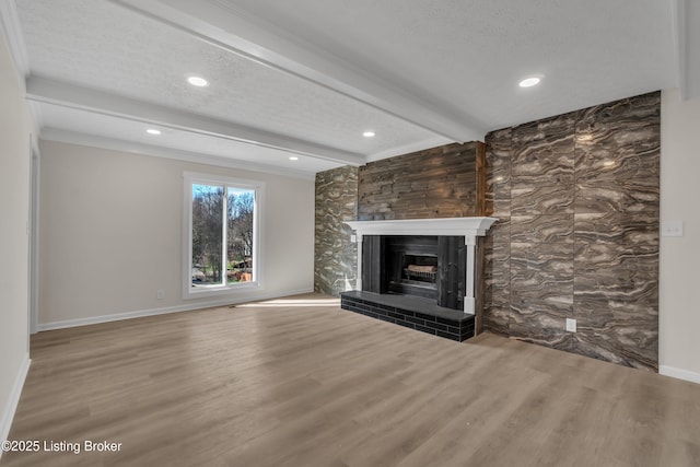 unfurnished living room with wood-type flooring, a textured ceiling, and beam ceiling