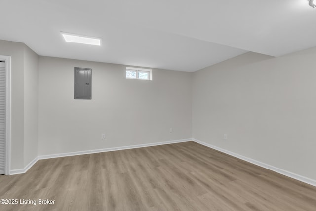 basement with electric panel and light hardwood / wood-style flooring