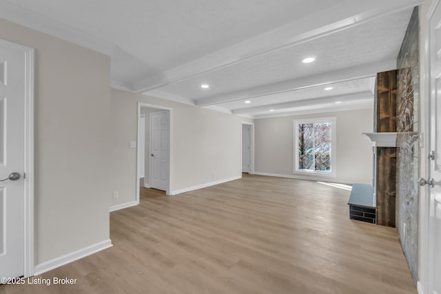 unfurnished living room featuring beamed ceiling and light wood-type flooring