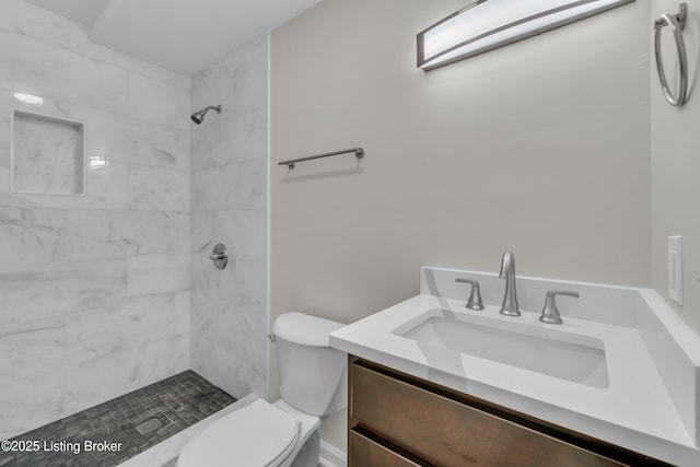 bathroom with vanity, toilet, and a tile shower