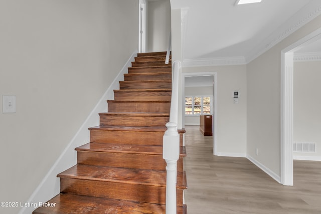 staircase featuring crown molding and wood-type flooring