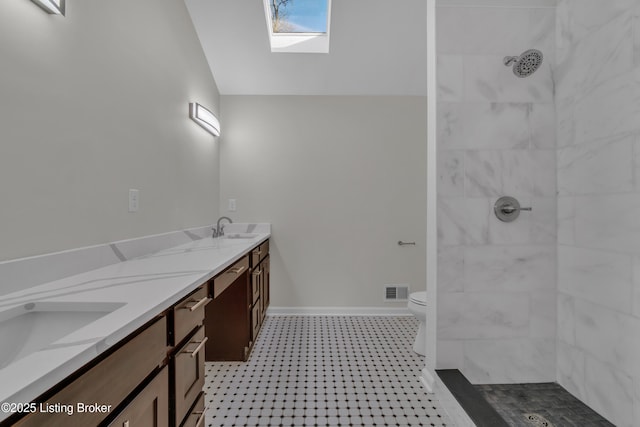 bathroom with vanity, vaulted ceiling with skylight, toilet, and a tile shower