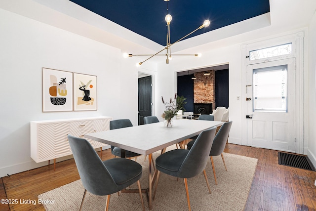 dining area with wood-type flooring, radiator, and a tray ceiling