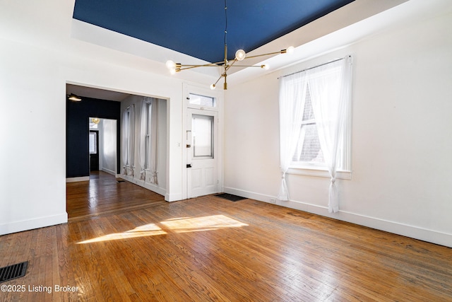 spare room featuring hardwood / wood-style flooring and a notable chandelier