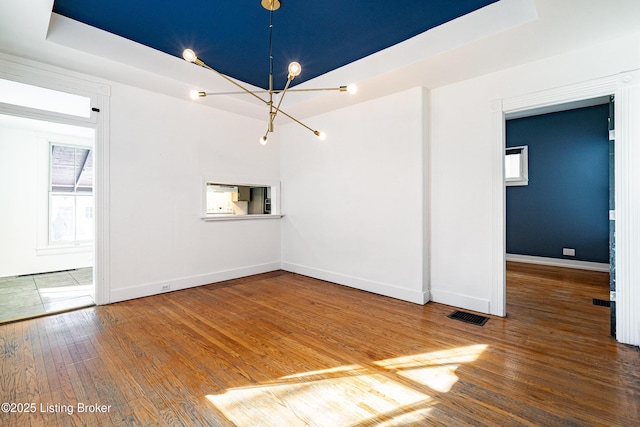 spare room with hardwood / wood-style floors and a raised ceiling