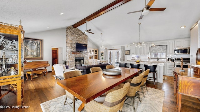 dining room featuring hardwood / wood-style flooring, a fireplace, beam ceiling, and a ceiling fan